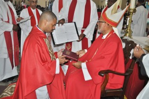 Rev. Olando Gayle, newly-ordained Priest, receives a Bible from the Lord Bishop.