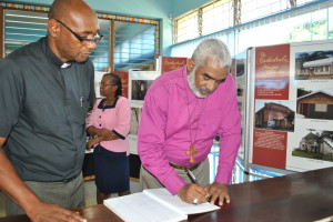 The Very Rev. Canon Collin Reid (left), Rector of the Cathedral, observes as Bishop Thompson writes his comment on the exhibition in the Visitor's Book