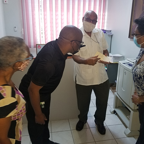 Archbishop Gregory shows his Vaccination Certificate to Miss Beverley Newell, Communication Officer; Rev. Craig Mears, Director of Youth Ministries and Mrs. Jacqueline Mighty, Diocesan Secretary.